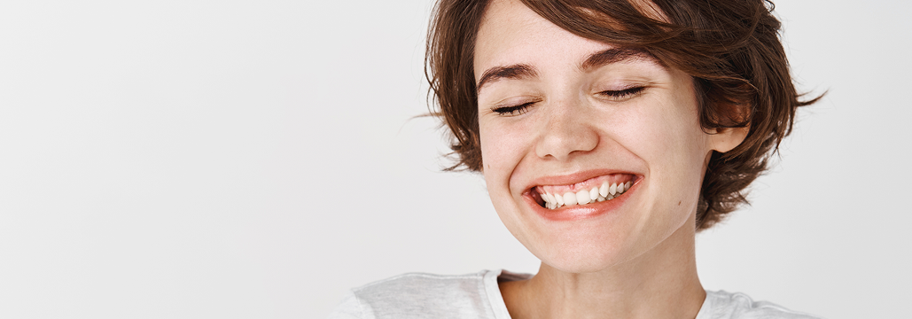 Young woman with short dark hair smiling with eyes closed